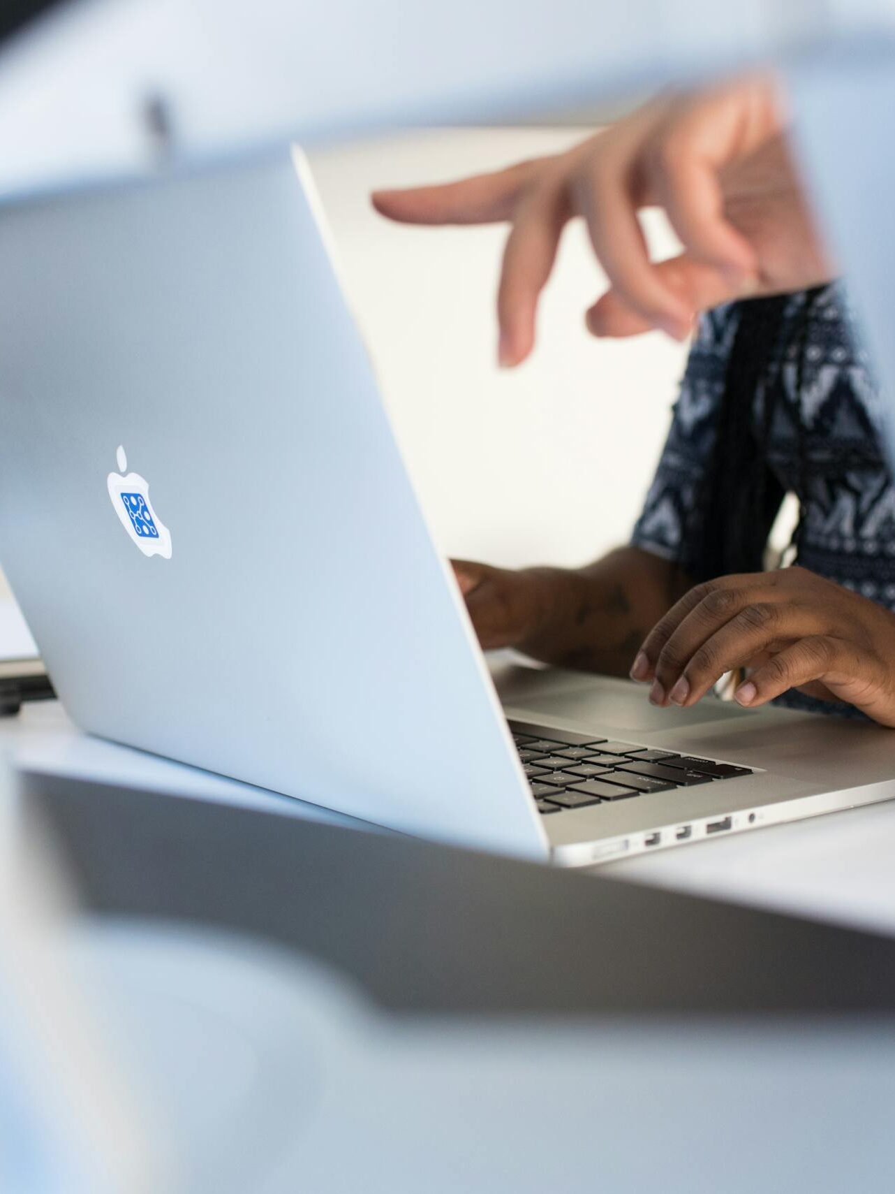 Hands working on a laptop in a modern tech office, showcasing teamwork and technology.